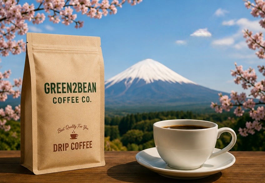 A Green2bean coffee bag and a fresh cup of coffee on a wooden table, with Mount Fuji and cherry blossom behind
