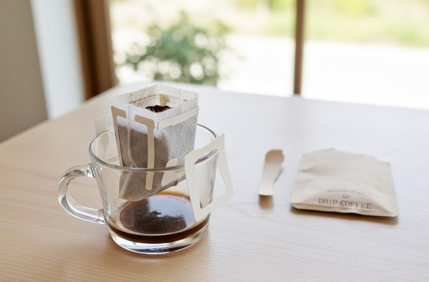 A drip pouch hanging over a glass as coffee brews through